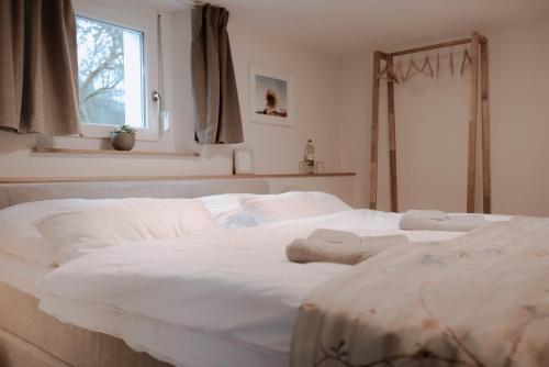 a large white bed in a bedroom with a window at Ferienwohnung am Kirchbrunnen in der Rhön, pure Erholung in traumhafte Betten! in Urspringen