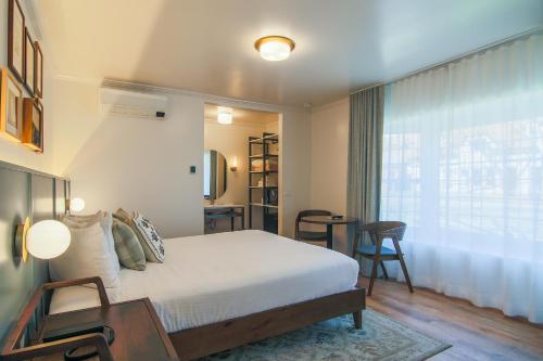 ein Schlafzimmer mit einem Bett, einem Schreibtisch und einem Fenster in der Unterkunft Solvang Inn & Cottages in Solvang