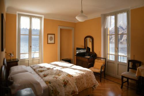 a bedroom with a bed and a desk and windows at Hotel Olivedo in Varenna