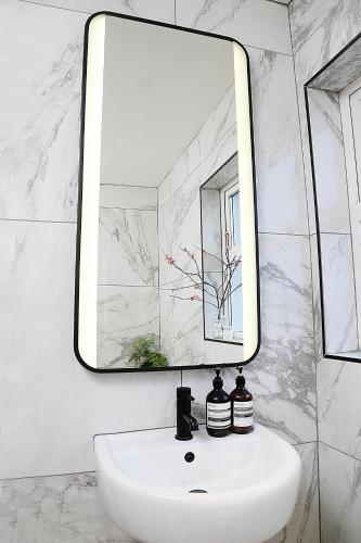 a bathroom with a white sink and a mirror at Newly refurbished home on the North Coast - AONB in Bushmills