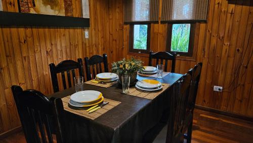 a dining room table with a black table cloth and plates and chairs at La Floresta - Cabañas con Naturaleza y Tranquilidad in Puerto Iguazú