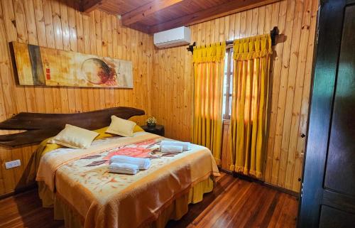a bedroom with a bed in a room with wooden walls at La Floresta - Cabañas con Naturaleza y Tranquilidad in Puerto Iguazú