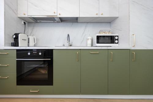 a kitchen with green cabinets and a microwave at Imedio Olive Apartment Aviatiei in Bucharest