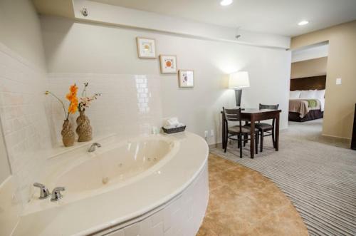 a large white bathroom with a tub and a bedroom at SureStay Plus by Best Western Corydon in Corydon