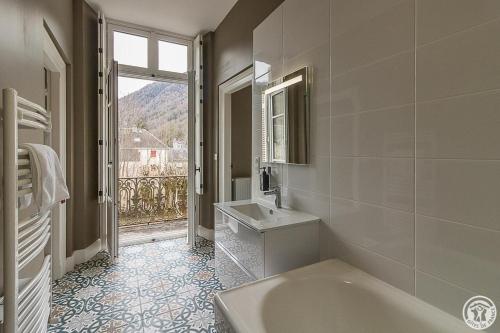 ein weißes Bad mit einer Badewanne und einem Fenster in der Unterkunft Villa du Lys in Luchon