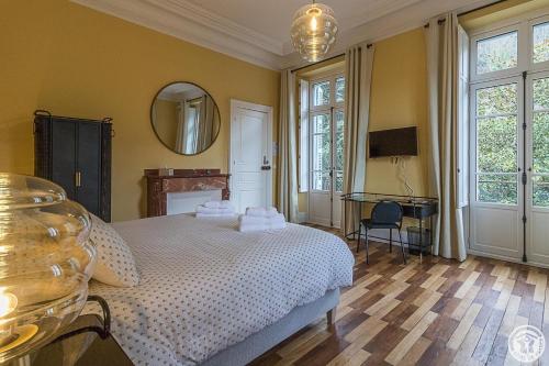 Schlafzimmer mit einem weißen Bett und einem Spiegel in der Unterkunft Villa du Lys in Luchon