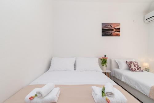 a white room with two beds and a couch at Aldino Rooms in Trogir