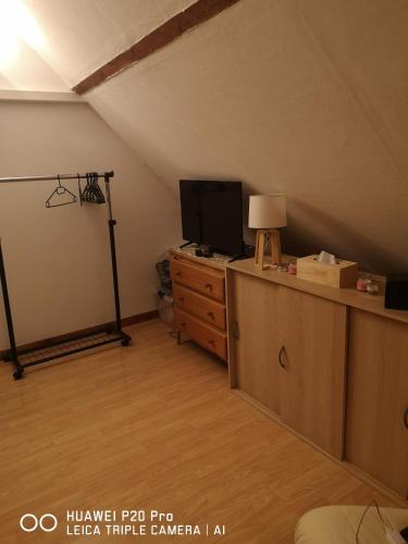 Cette chambre mansardée dispose d'une télévision et d'une commode avec une lampe. dans l'établissement Joli studio, à Sens