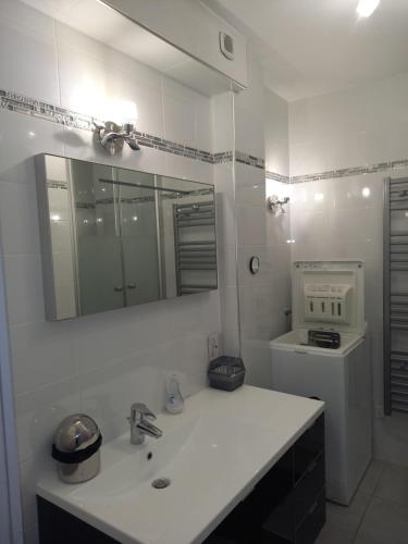 La salle de bains blanche est pourvue d'un lavabo et d'un miroir. dans l'établissement Bandol, T3, les pieds dans l'eau, presqu'île du Capelan, à Bandol