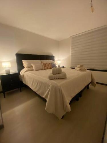 a bedroom with a large bed with two towels on it at Maravilloso Depto nuevo 2D 2B centro frente al lago con piscina techada temperada y jacuzzi in Puerto Varas