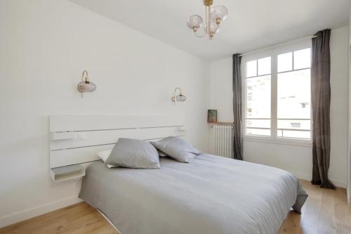 ein weißes Bett mit zwei Kissen im Schlafzimmer in der Unterkunft Appartement Nation in Paris