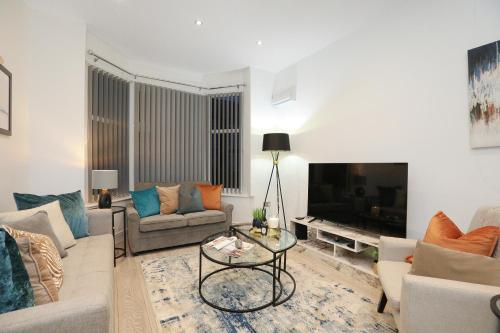 a living room with a couch and a tv at Leicester Serviced Accomodation, Sleeps 8 in Leicester