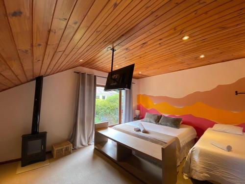 a bedroom with two beds and a wooden ceiling at Capivari Lodge vista incrível da natureza in Campos do Jordão