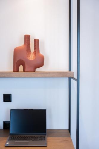 a laptop sitting on top of a shelf with a piece of art at Volos Inn Hotel in Volos