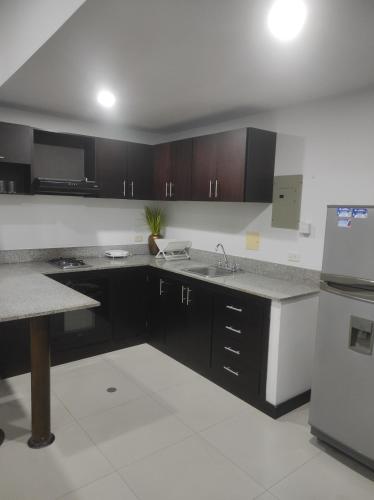 kuchnia z czarnymi szafkami, zlewem i lodówką w obiekcie Apartamento tipo Loft, Edificio Platino w mieście Rodadero