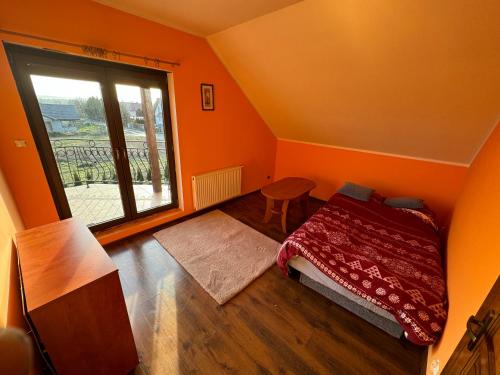 an orange room with a bed and a window at Dom Krotoszyce in Krotoszyce