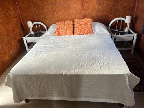 a bed with orange pillows and two night stands at 0 es 3 Dos in Treinta y Tres