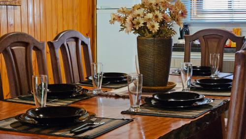 a table with plates and glasses and a vase of flowers at La Floresta - Cabañas con Naturaleza y Tranquilidad in Puerto Iguazú