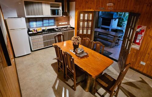 a kitchen with a wooden table with chairs and a refrigerator at La Floresta - Cabañas con Naturaleza y Tranquilidad in Puerto Iguazú