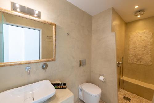 a bathroom with a sink and a toilet and a shower at Enalion White Suites Oia in Oia