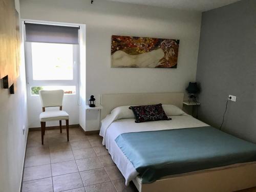 1 dormitorio con 1 cama, 1 silla y 1 ventana en Casa do Horreo, en Puentecesures