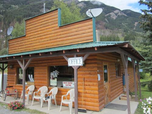 ein kleines Gebäude mit weißen Stühlen davor in der Unterkunft Mount Robson Lodge in Mount Robson
