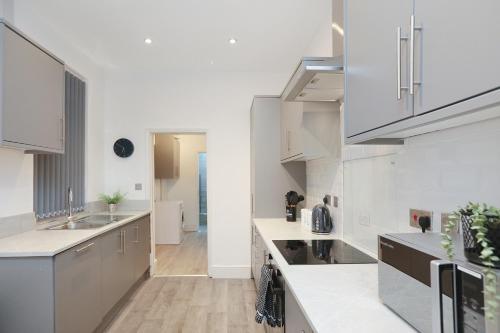 a kitchen with white cabinets and white counter tops at Leicester Serviced Accomodation, Sleeps 8 in Leicester