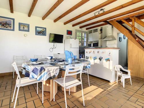 une cuisine avec une table, des chaises et un réfrigérateur dans l'établissement Résidence D22-ile Grande - Maison de pêcheur dans un jardin sur la mer MAE-3464, à Pleumeur-Bodou