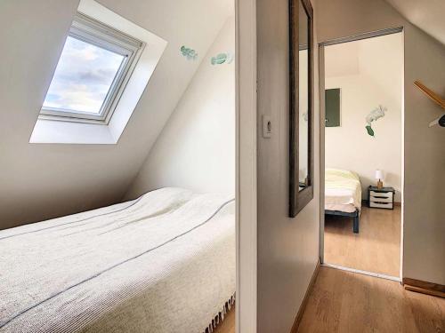 une chambre mansardée avec un lit et une fenêtre dans l'établissement Résidence D22-ile Grande - Maison de pêcheur dans un jardin sur la mer MAE-3464, à Pleumeur-Bodou
