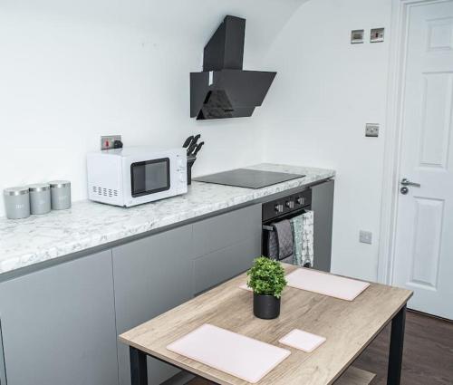 a kitchen with a table and a microwave on a counter at Aylesbury Studio-1 with free parking in Buckinghamshire