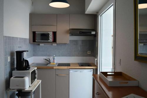 une cuisine avec un évier et un micro-ondes dans l'établissement Résidence Les Sept Iles - Vacances vue mer à 180°et les pieds dans l'eau ! MAE-3504, à Trégastel