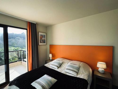 une chambre avec un lit avec une tête de lit orange et un balcon dans l'établissement Résidence L'archipel - Appartement au pied de la plage de Trestraou MAE-3554, à Perros-Guirec