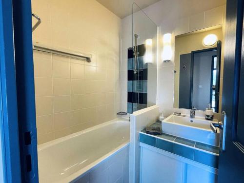 une salle de bain avec une baignoire blanche, un lavabo et un miroir dans l'établissement Résidence L'archipel - Appartement au pied de la plage de Trestraou MAE-3554, à Perros-Guirec