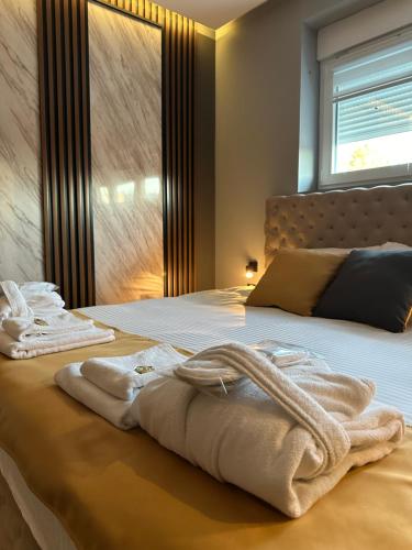 a bedroom with a bed with towels on it at MOZAIK APARTMENTS & SPA - Modern 4-Star Apartments with Exclusive Private SPA WELLNESS in the City Center - SAUNA, JACUZZI, TURKISH BATH - FREE PARKING, Wi-FI - Rooms & Apartments Cuprija in Ćuprija