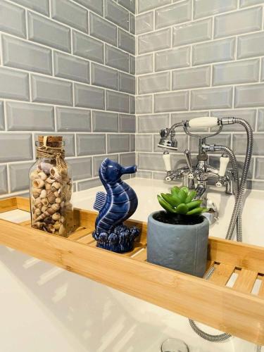 un lavabo de salle de bain avec une statue de dinosaure bleu sur une étagère dans l'établissement Résidence G78-tregastel - Maison avec jardin près du Coz Pors à Trégastel MAE-3574, à Trégastel