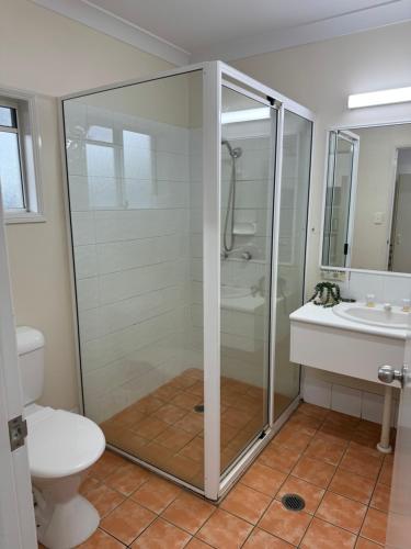 a bathroom with a shower and a toilet and a sink at Mareeba Motor Inn in Mareeba