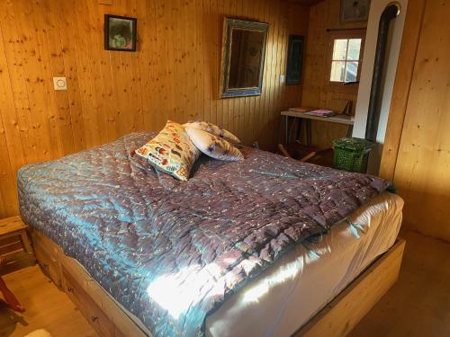 una camera da letto con letto in una camera in legno di Un nid au paradis - Chalet traditionnel avec beaucoup de cachet a Mayoux