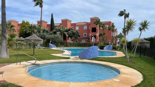 a swimming pool in front of a large building at CASA EVA Naturista, Vera Playa in Playas de Vera