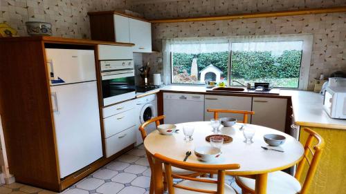 Il comprend une cuisine équipée d'une table avec des chaises et d'un réfrigérateur blanc. dans l'établissement Résidence C78-tregastel - Guz Heol maison proche plage de la Grève Blanche MAE-3744, à Trégastel