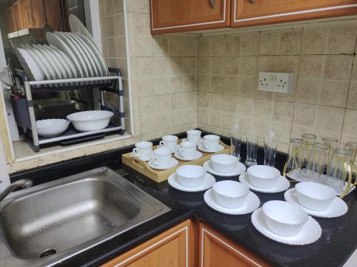 a kitchen counter with plates and cups and a sink at Arnim Suite - 3 Bedrooms Apartment in Sharjah