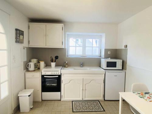 une cuisine avec des armoires blanches, un évier et un micro-ondes dans l'établissement Résidence C26-tregastel - Appartement dans villa à 100 mètres de la plage MAE-3034, à Trégastel