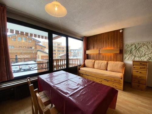 Cette chambre comprend une table, un canapé et une fenêtre. dans l'établissement Résidence Neves - VAL THORENS location: studio pour 4 personnes dans un quartier jeune et animé LES NEVES MAE-9062, à Val Thorens