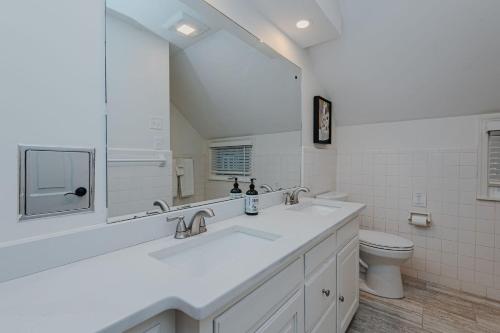 uma casa de banho branca com 2 lavatórios e um WC em Artopia Retreat em Greensboro
