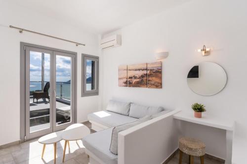 a white living room with a couch and a table at Enalion White Suites Oia in Oia