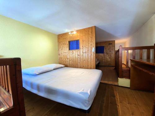 une chambre avec un lit blanc et des murs en bois dans l'établissement Résidence Silveralp - VAL THORENS location: Proche garderie et école de ski, appartement 4 pers avec mezzanine MAE-9083, à Val Thorens