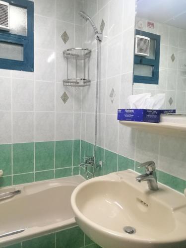 ein Badezimmer mit einem Waschbecken und einer Badewanne in der Unterkunft Roomstay Abu Dhabi in Abu Dhabi