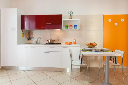 a kitchen with white cabinets and a table with chairs at Settessenze Residence & Rooms in Agropoli