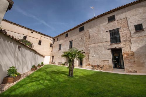 un patio con una palmera frente a un edificio en La casa de las flores, en Toro