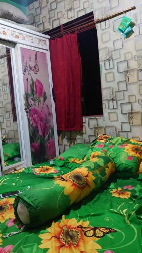 a bed with a green comforter with bugs on it at RISKY HOUSE in Sampit