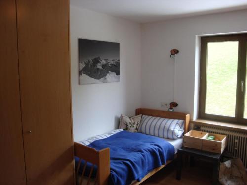 上萊希的住宿－Oberlech，一间卧室设有蓝色的床和窗户。